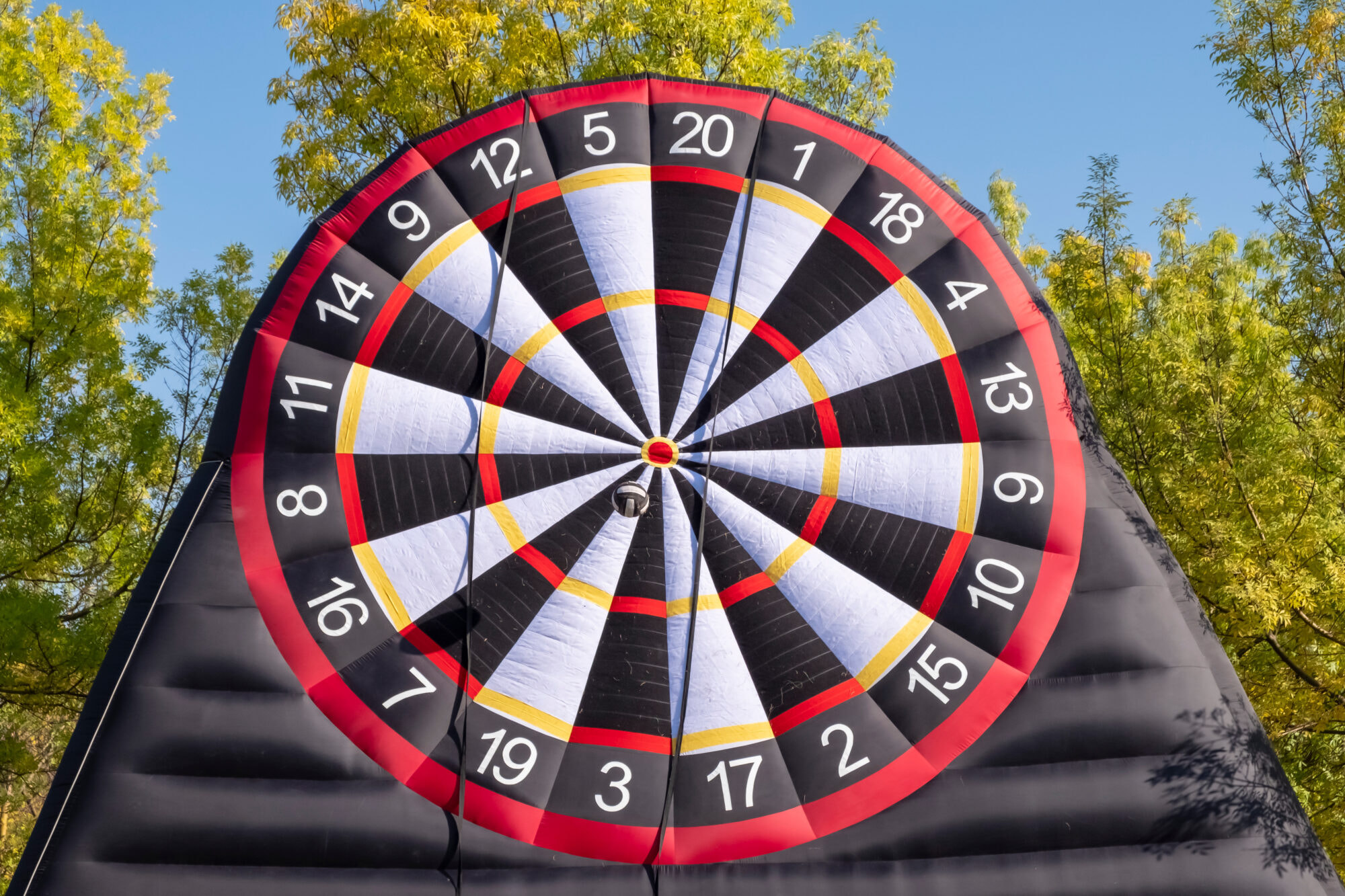 Giant inflatable dart board with velcro ball in autumn park.